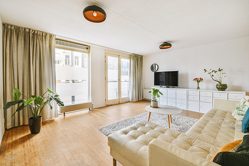 A modern living room with a light design, a large beige sofa on the parquet floor of a cozy house