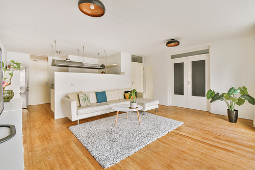 A modern living room with a light design, a large beige sofa on the parquet floor of a cozy house