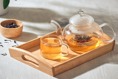 Tea in a transparent cup and teapot on a wooden background