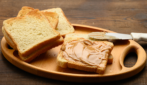 peanut butter on a square slice of white wheat flour, breakfast