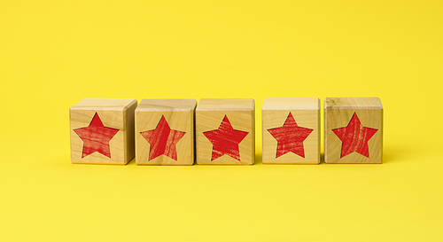 five wooden cubes with a red star on a yellow background. Quality assessment concept, rating. Best service and high business valuation. User reviews