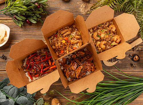 Chinese restaurant take-out box with various food on wooden background, top view