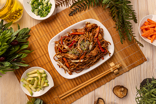 Stir fry noodles with chicken and vegetables in a white plate
