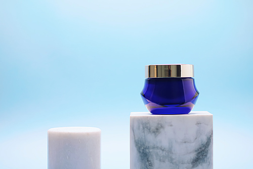 Facial cream jar on blue background, luxury skincare products, beauty and cosmetics.