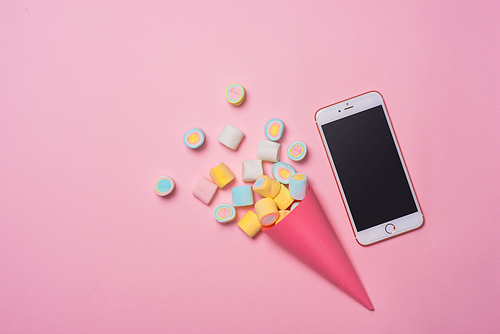 Birthday concept. Top View various sweet candies with smartphone showing screen.