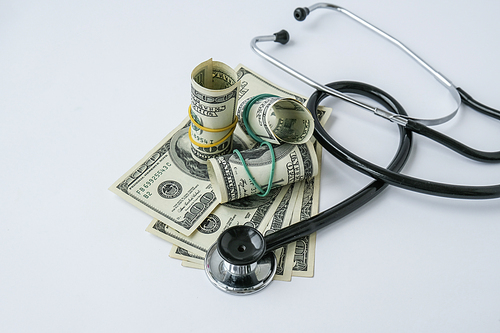 Stack of cash dollars and stethoscope. The concept of medical expensive medicine, doctors salary. Copy space for text. Health Life insurance. vaccination costs. Financial crisis. Covid-19 crimes