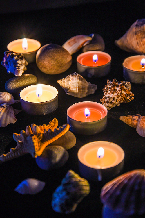 Candles, stones and shell in spa, light at night, sea spa concept, composition of spa treatment, selective focus