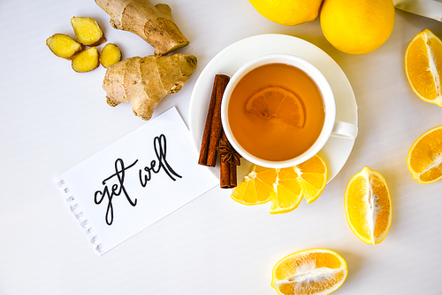 GET WELL - written on piece of paper among the products for the treatment of common cold - lemon, ginger, chamomile tea. Vitamin natural drink. Cinnamon anise star.