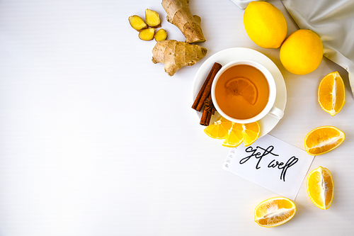 GET WELL - written on piece of paper among the products for the treatment of common cold - lemon, ginger, chamomile tea. Vitamin natural drink. Cinnamon anise star.