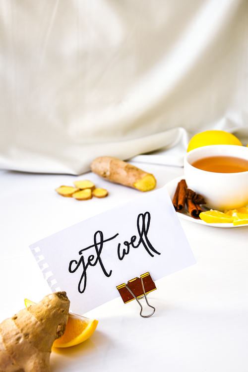 GET WELL - written on piece of paper among the products for the treatment of common cold - lemon, ginger, chamomile tea. Vitamin natural drink. Cinnamon anise star.