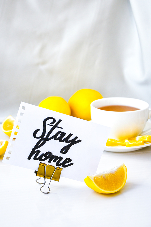 STAY HOME- written on piece of paper among the products for the treatment of common cold - lemon, ginger, chamomile tea. Vitamin natural drink. Cinnamon anise star.