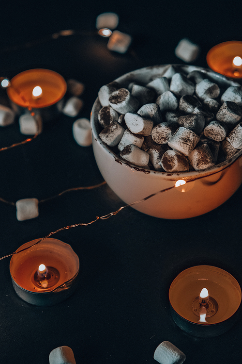 Cup with hot winter cacao and marshmallows at night. Christmas lights. Tea light candles. Good night sweet dreams. Cozy winter days. Hygge.