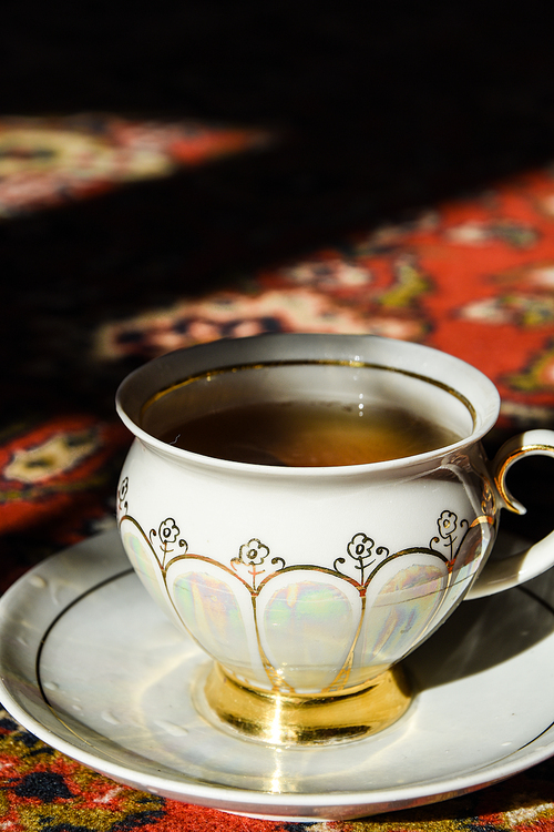 vintage porcelain tea time on turkish carpet, black tea with smoke in a china cup and saucer on the sunlight, Asian tea ceremony, Hot steam