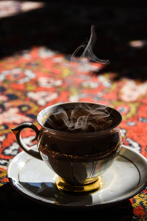 vintage porcelain tea time on turkish carpet, black tea with smoke in a china cup and saucer on the sunlight, Asian tea ceremony, Hot steam
