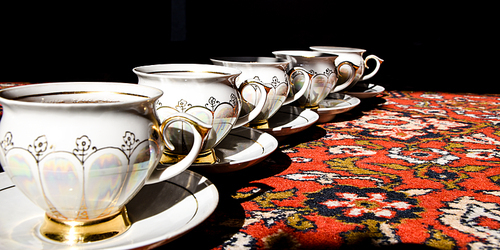 vintage soviet porcelain cups of tea with saucers on turkish carpet, traditional tea ceremony, sunlight with deep shadows
