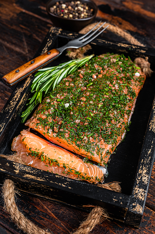 Salmon Gravlax cured with dill and salt in wooden tray. Dark wooden background. Top view.