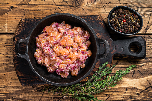 Tartar or tartare with salmon fish, red onion, arugula and capers in a pan. Wooden background. Top View.