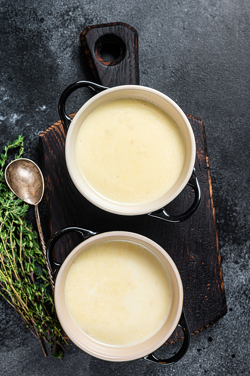 Potato cream soup in bowls on kitchen table. Black background. Top view.