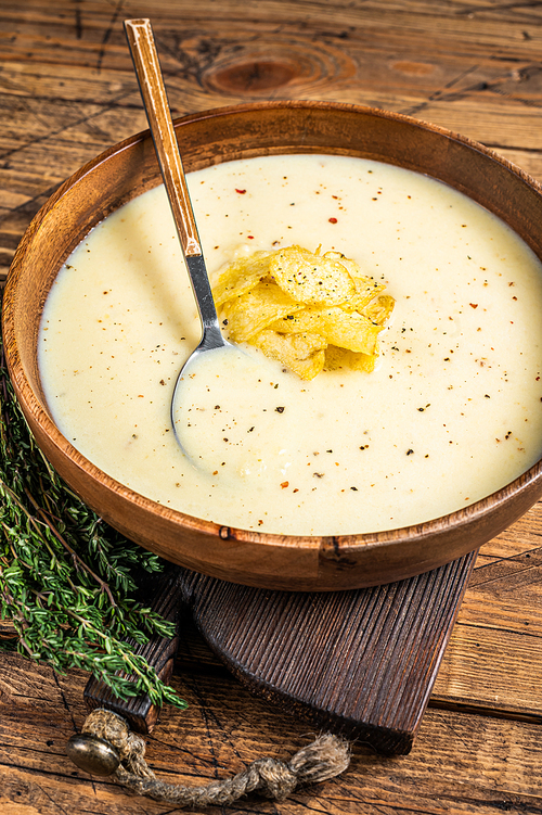Cream potato soup with potato chips in wooden plate. wooden background. Top view.