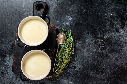 Potato cream soup in bowls on kitchen table. Black background. Top view. Copy space.