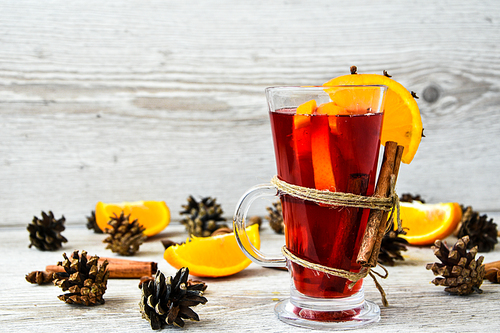 Christmas mulled wine with spices and orange on wooden rustic background. Selective focus. Anise stars and cinnamon sticks. Christmas cones. Copy space for text