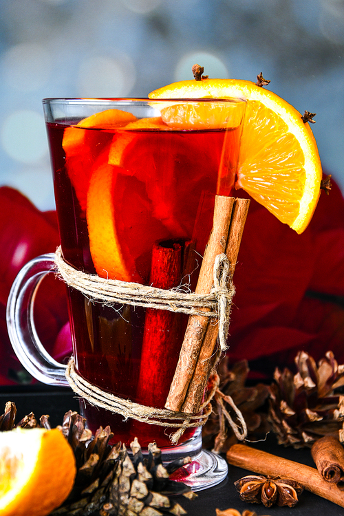 Christmas drink. Glasses of hot mulled wine with oranges, anise and cinnamon next to the red poinsettia flower. Holiday atmosphere, Rustic style. The idea for creating greeting cards