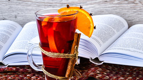 Mulled wine Hot christmas drink with spices on wooden background. Orange slice, cinnamon sticks, books and sweater. Christmas morning. Holiday atmosphere, Rustic style. The idea for creating greeting cards. Autumn beverage