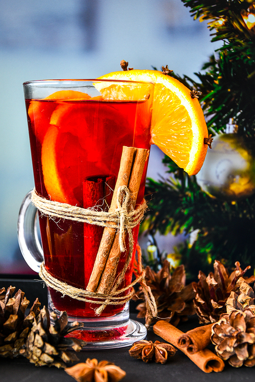 Mulled wine Hot christmas drink with spices on a dark background. Orange slices, cinnamon sticks, christmas cones, bright bokeh. Holiday atmosphere, Rustic style. The idea for creating greeting cards