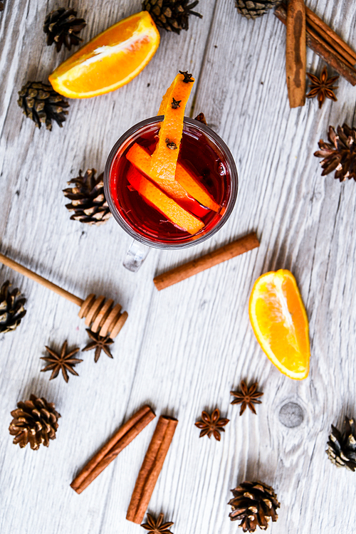 Christmas mulled wine with spices and orange on wooden rustic background. Selective focus. Anise stars and cinnamon sticks. Christmas cones. Copy space for text. Top view