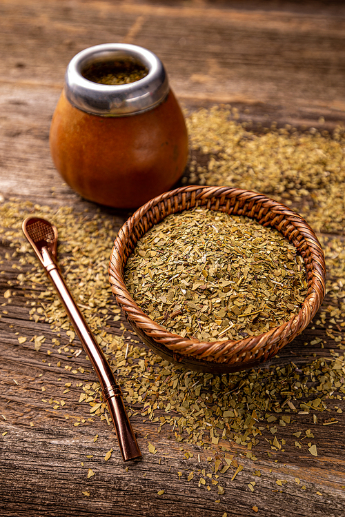 Yerba mate leaves in wooden bowl on wooden background