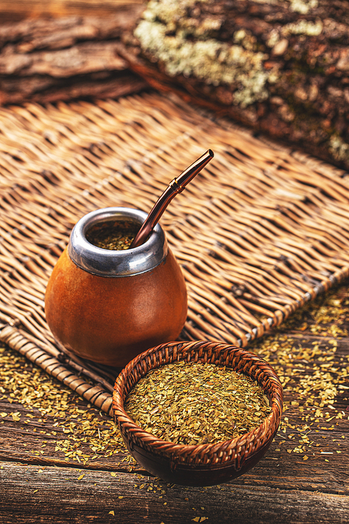 Composition of yerba mate South American tea, dried leaves in wooden bowl and mate calabash with bombilla