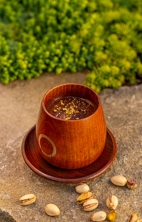 Wooden cup of hot chocolate drink with pistachio