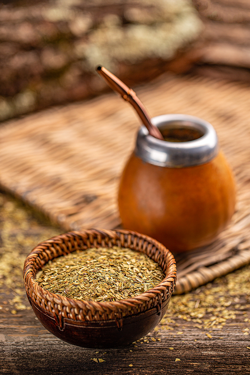 Yerba mate leaves in wooden bowl on wooden background