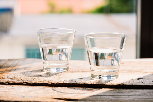 Two glasses of water on table on wooden background