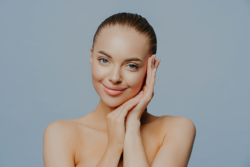 Beauty woman face portrait. Beautiful spa model girl with perfect fresh clean skin on blue background. Brunette female looking at camera. Youth and skin care concept.