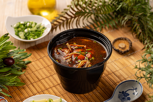 Take out noodle soup with chicken and vegetable in plastic black bowl