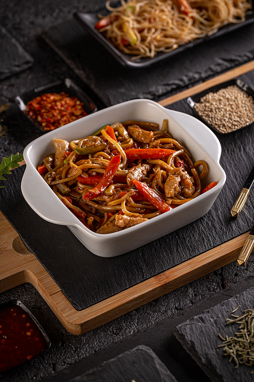 Slices of chicken with vegetables in spicy sauce served with pasta, Chinese main course