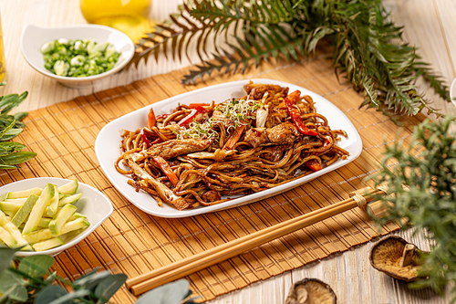 Chinese style chicken fried noodles with veggies, studio shot