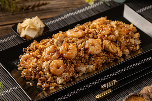 Seafood fried rice with brown sauce in black plate