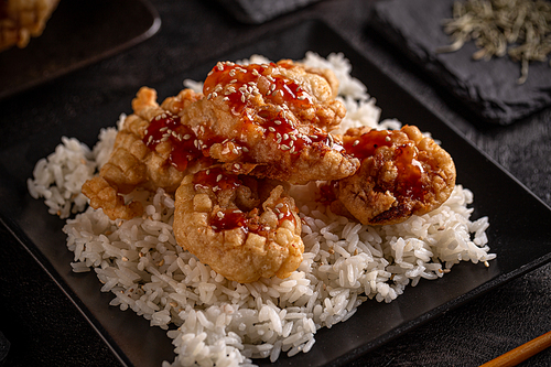 Battered fried shrimp in a black plate served with rice