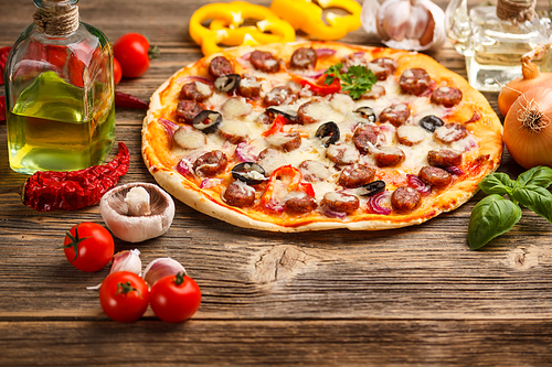 Pizza with ingredients on rustic wooden table