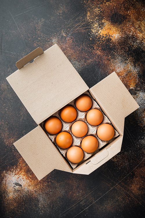 Chicken eggs in an egg box tray set, on old dark rustic background, top view flat lay