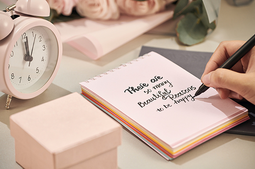 Woman hands holding pen, ready to write. Pink rose,  pen and gift with pink heart on white table. Love concept. Saint Valentine's Day concept. Mother's day concept.