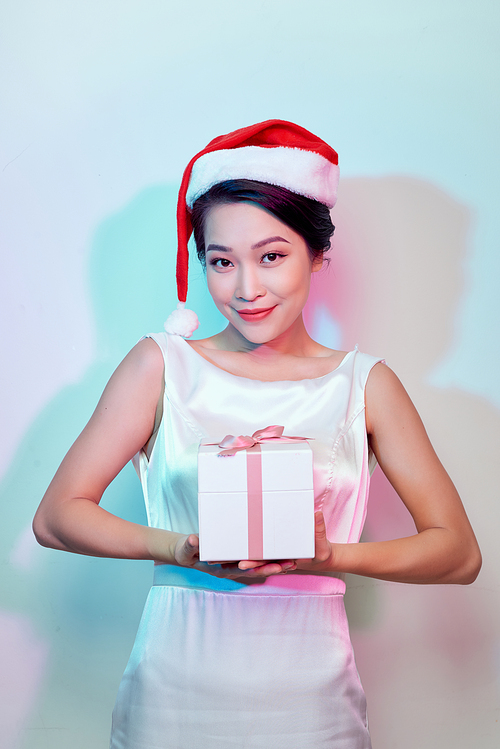 Happy excited young woman in santa claus hat with gift box over light background