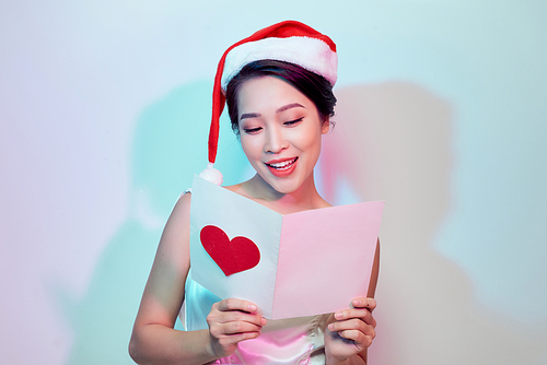 beautiful young woman holding a valentine postcard with a pink heart on light background