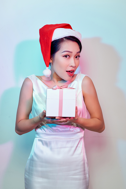 Happy excited young woman in santa claus hat with gift box over light background