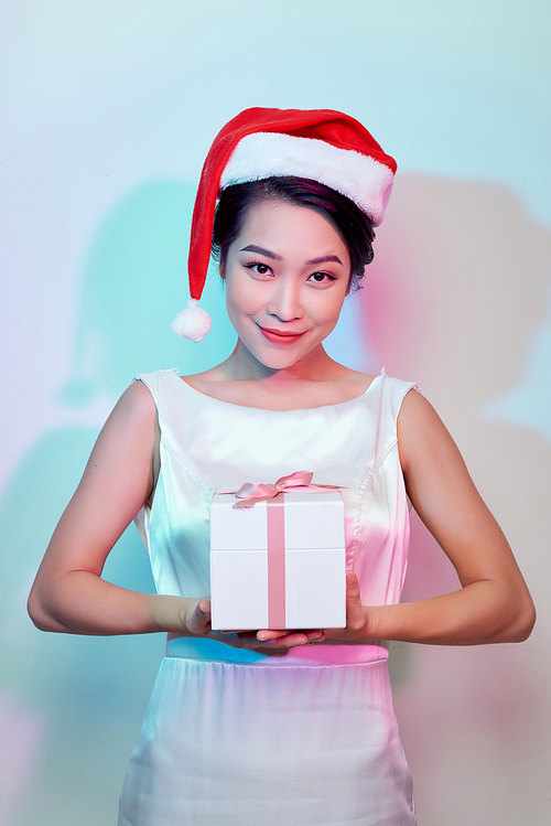 Happy excited young woman in santa claus hat with gift box over light background