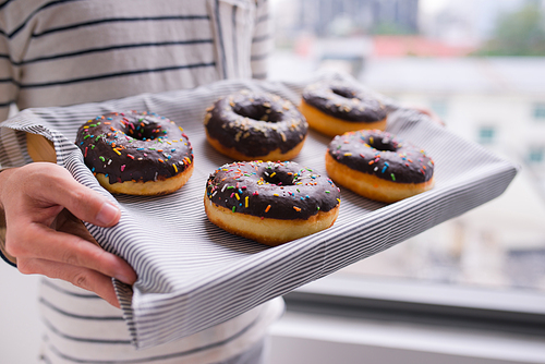 Male hands holding a tray of donuts