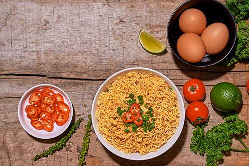 noodle in bowl and ingredients on wood background top view