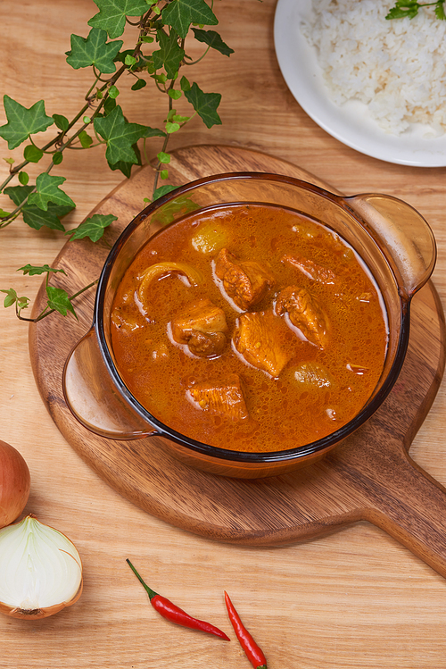 Chicken curry with spice in pot on wooden background